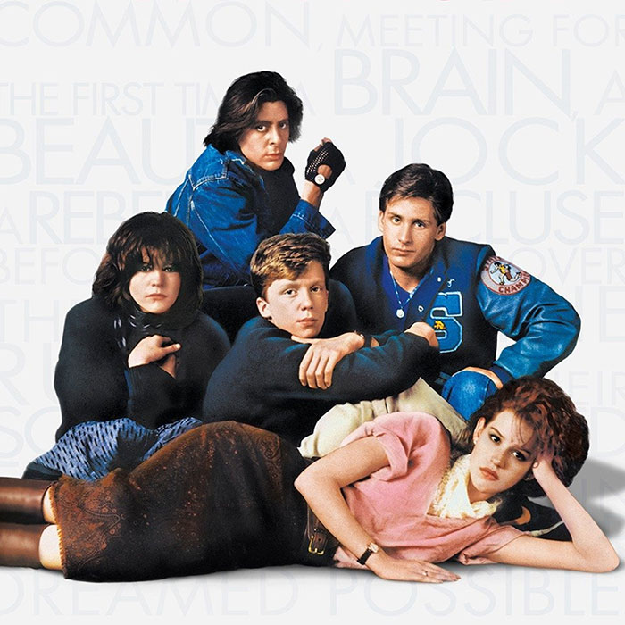 Groupe de cinq adolescents aux looks typiques des années 80, tiré du film culte The Breakfast Club, avec vestes en jean, pulls oversize, jupes longues, veste de sport varsity et accessoires rétro incarnant les stéréotypes lycéens de l’époque.