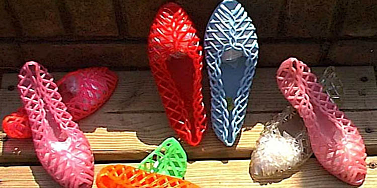 Collection de ballerines ajourées en plastique coloré, typiques des années 80, avec des modèles rouges, roses, bleus, verts et translucides posés sur un sol en bois au soleil.