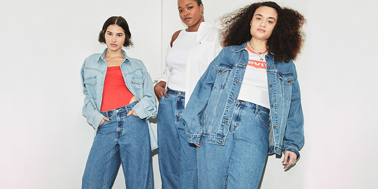 Trois femmes portant des looks en jean oversize inspirés des années 80, avec vestes en denim larges, jeans taille haute et tops basiques pour un style rétro casual et assumé.